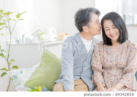 一對中年男女坐在客廳的沙發上，在耳邊竊竊私語 84342659