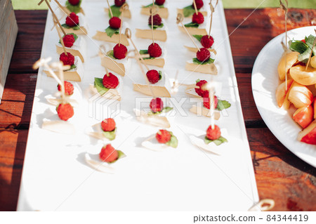 a lot of small cheescakes with raspberries on them 84344419