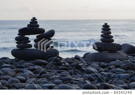 Stone piles made along a beach and the sea in the background 84345249