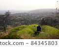 A lover snuggling up to the city of Los Angeles from the top of the hill 84345803