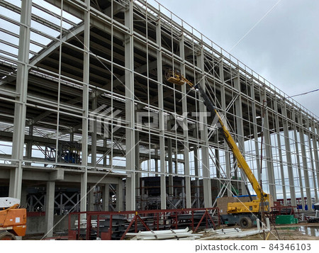 truck crane with spread out legs and an extended boom is at construction site truck crane with spread out legs and an extended boom is at construction site 84346103