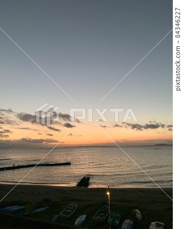 夕陽下的天空浮著雲朵，海灘上平靜的海浪 照片素材 84346227