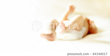 image of the legs of the baby lying on the bed. blurred image for the advertising text. 84348017