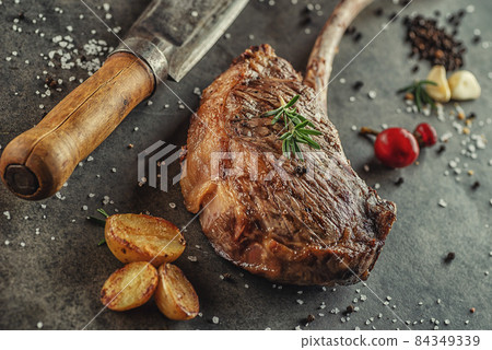 Grilled beef tomahawk steak fillet with ingredients and herbs on black board, product image for restaurant 84349339