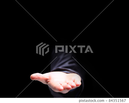 The palm of the hand to the top, on a black background. 84351567