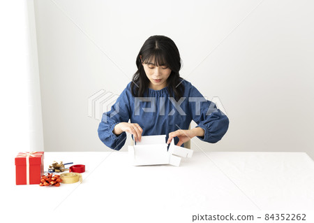 A woman assembling a gift box at a desk 84352262