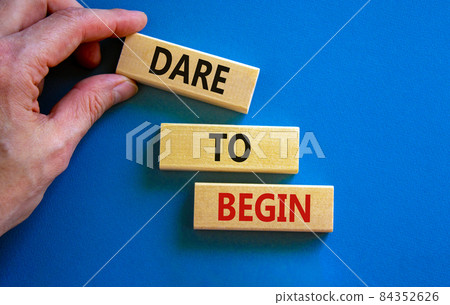 Dare to begin symbol. Wooden blocks with words 'Dare to begin'. Beautiful blue background, businessman hand. Business, dare to begin concept, copy space. Dare to begin symbol. Wooden blocks with words 'Dare to begin'. Beautiful blue background, businessman hand. Business, dare to begin concept, copy space. 84352626
