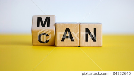 Fliped cube, changed the word man to can. Beautiful yellow table, white background. Copy space. Business and motivational concept. Fliped cube, changed the word man to can. Beautiful yellow table, white background. Copy space. Business and motivational concept. 84352640