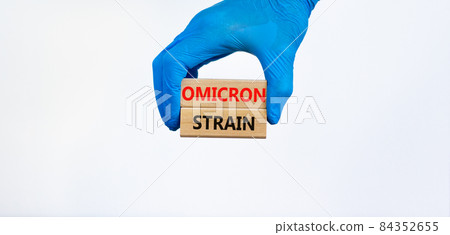 Covid-19 new omicron strain symbol. Hand in blue glove, wooden blocks, words Omicron strain. Beautiful white background. Copy space. Medical and COVID-19 new omicron strain variant virus concept. Covid-19 new omicron strain symbol. Hand in blue glove, wooden blocks, words Omicron strain. Beautiful white background. Copy space. Medical and COVID-19 new omicron strain variant virus concept. 84352655