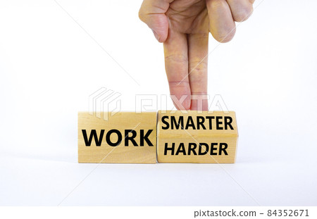 Work harder or smarter symbol. Businessman turns wooden block and changes words 'work harder' to 'work smarter'. Beautiful white background, copy space. Business and work harder or smarter concept. Work harder or smarter symbol. Businessman turns wooden block and changes words 'work harder' to 'work smarter'. Beautiful white background, copy space. Business and work harder or smarter concept. 84352671