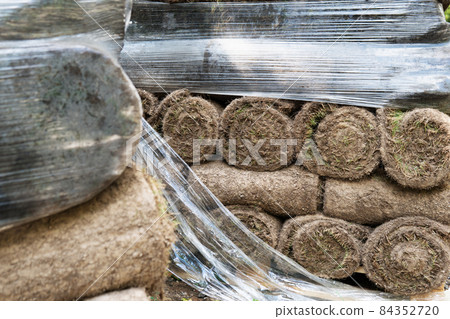 Grass turf rolls piled up on the Moscow street during road repairs in summer Grass turf rolls piled up on the Moscow street during road repairs in summer 84352720