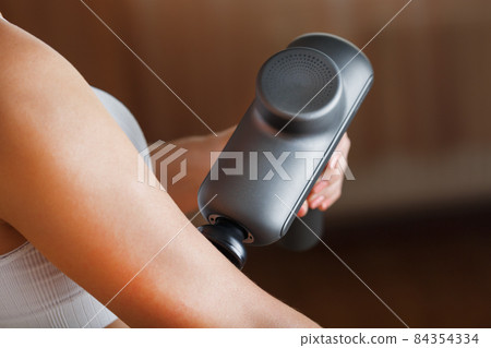 Self-massage of women's hands using a percussion gun at home. Self-massage of women's hands using a percussion gun at home. 84354334