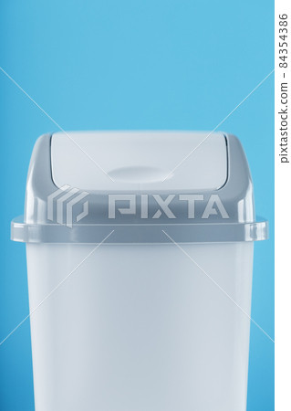 White trash can on a light blue background with free space. 84354386