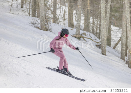 Alpine Skiing Downhill. Woman on ski going downhill having fun on the slopes on a snowy day - Winter sport and activities. Cool ski clothing, goggles and helment. Good skier 84355221