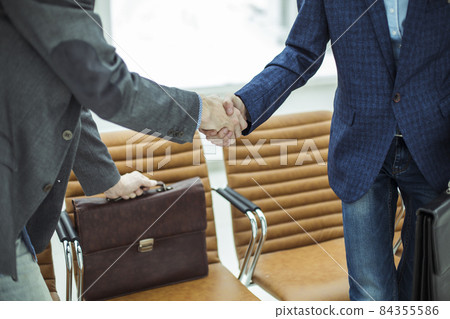 employees of the company with briefcases shaking hands in the lobby of a modern office 84355586