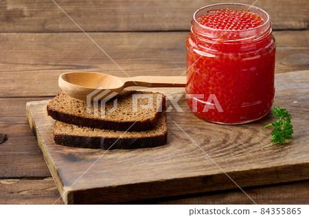full glass jar with red caviar on a brown wooden table full glass jar with red caviar on a brown wooden table 84355865