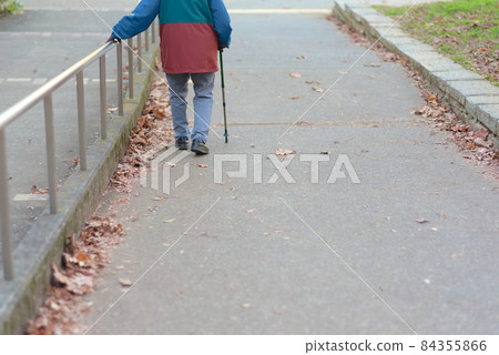 Elderly people walking with a cane and a handrail Elderly people walking with a cane and a handrail 84355866