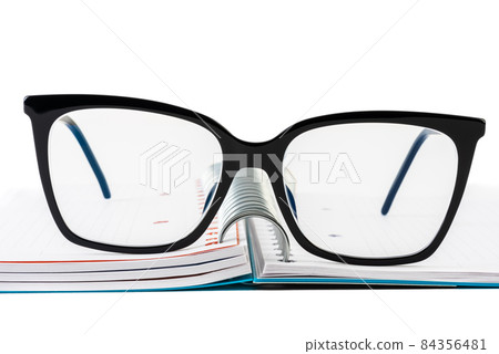 Reading glasses on opened ring binder notebook 84356481