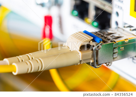Fiber optic patch cord with gbic connected to switch in data center, selective focus close-up view Fiber optic patch cord with gbic connected to switch in data center, selective focus close-up view 84356524