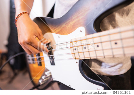 close up of a bassist's hand strumming electric guitar bass strings while checking sound close up of a bassist's hand strumming electric guitar bass strings while checking sound 84361361