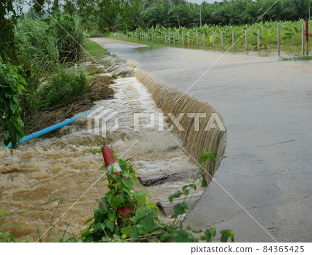 Brown water flood  flowing and flooding concrete road, Flood in rainy season, Thailand 84365425