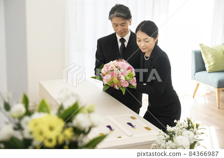 Middle-aged men and women offering a bouquet to the casket Family funeral Home funeral image 84366987