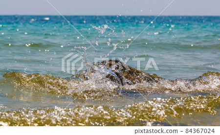 Waves hitting round rocks and splashing Waves hitting round rocks and splashing 84367024