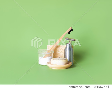 Bamboo toothbrush, steel razor and one natural soap against green background. Bamboo toothbrush, steel razor and one natural soap against green background. 84367351