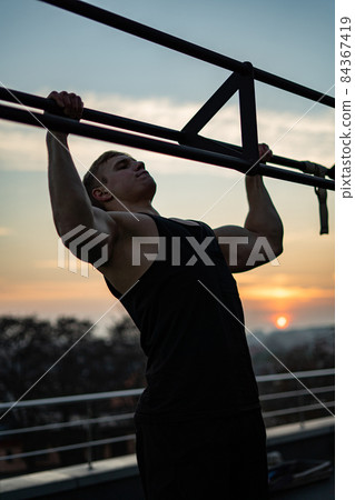 Muscular man doing pullups on sunset sky background. Concept of willpower, motivation and passion 84367419