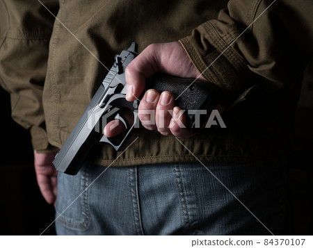 Man hiding a gun behind his back 84370107