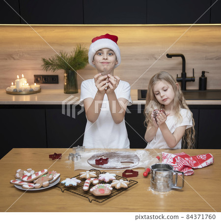 Children - a boy and a girl are preparing gingerbread in the kitchen Children - a boy and a girl are preparing gingerbread in the kitchen 84371760