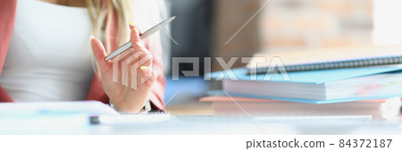 Business woman holding silver ballpoint pen at table with folders closeup 84372187
