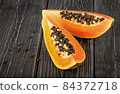Two pieces of ripe papaya on a wooden table 84372718