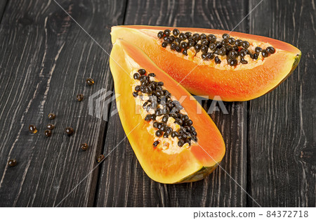 Two pieces of ripe papaya on a wooden table Two pieces of ripe papaya on a wooden table 84372718