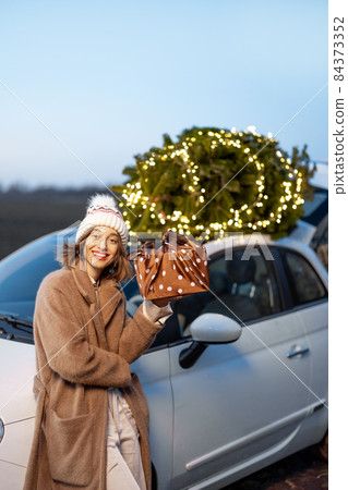 Happy woman with gifts and Christmas tree outdoors 84373352