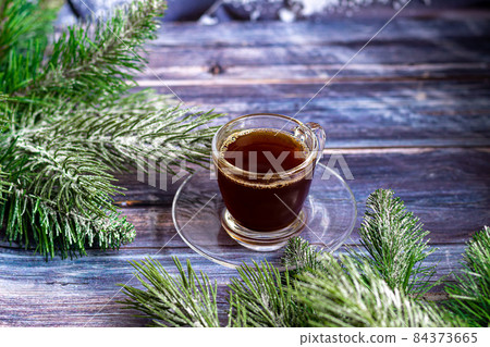 A cup of aromatic coffee with brown sugar, Christmas decorations, branches of a Christmas tree. Holiday concept New Year. On a wooden background. A cup of aromatic coffee with brown sugar, Christmas decorations, branches of a Christmas tree. Holiday concept New Year. On a wooden background. 84373665