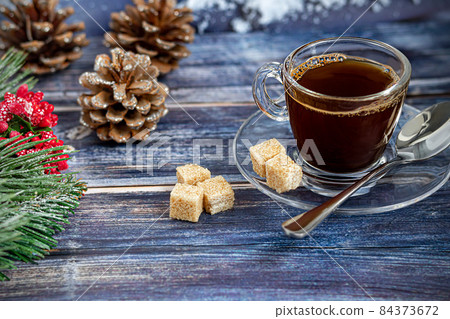 A cup of aromatic coffee with brown sugar, Christmas decorations, branches of a Christmas tree. Holiday concept New Year. On a wooden background. 84373672