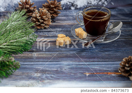 A cup of aromatic coffee with brown sugar, Christmas decorations, branches of a Christmas tree. Holiday concept New Year. On a wooden background. A cup of aromatic coffee with brown sugar, Christmas decorations, branches of a Christmas tree. Holiday concept New Year. On a wooden background. 84373673