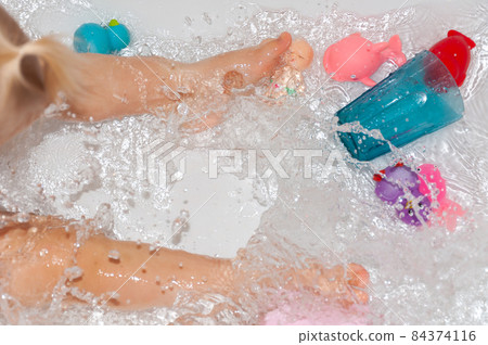 Splashing water in the bathtub with children's toys while bathing. Splashing water in the bathtub with children's toys while bathing. 84374116