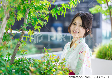 一個穿著浴衣走在城市裡的年輕女人 84374231
