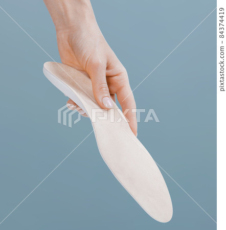 Orthopedic insole isolated on a blue background. Medical insoles. Treatment and prevention of flat feet and foot diseases. Foot care, feet comfort. Wear comfortable shoes. Flat Feet Correction. Orthopedic insole isolated on a blue background. Medical insoles. Treatment and prevention of flat feet and foot diseases. Foot care, feet comfort. Wear comfortable shoes. Flat Feet Correction. 84374419