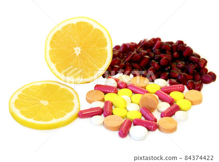 Various vitamins and other pills near lemon slices and pomegranate seeds. Various vitamins and other pills near lemon slices and pomegranate seeds. 84374422