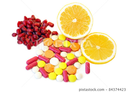 Various vitamins and other pills near lemon slices and pomegranate seeds isolated on white background. Various vitamins and other pills near lemon slices and pomegranate seeds isolated on white background. 84374423