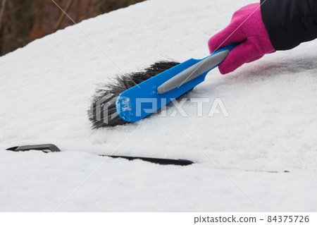 Hand of woman using brush and remove snow from car and windscreen Hand of woman using brush and remove snow from car and windscreen 84375726