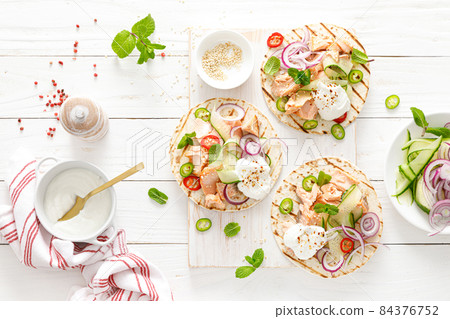 Spicy tacos with grilled salmon, vegetables, ricotta cheese, chili and fresh mint 84376752
