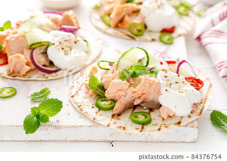 Spicy tacos with grilled salmon, vegetables, ricotta cheese, chili and fresh mint 84376754