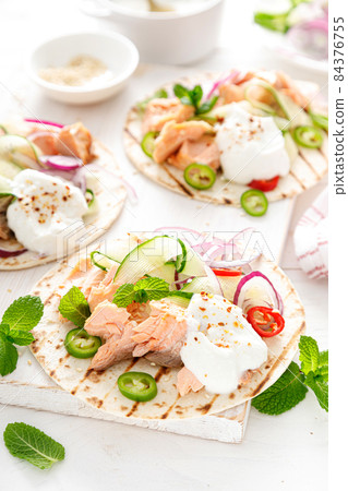 Spicy tacos with grilled salmon, vegetables, ricotta cheese, chili and fresh mint 84376755