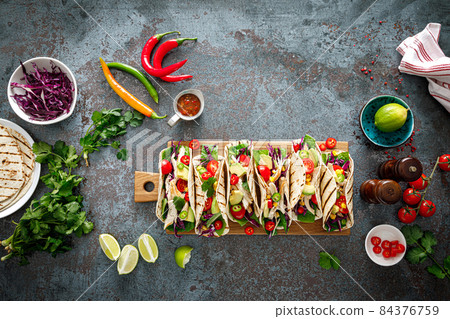 Chicken tacos with grilled meat, avocado, fresh vegetable salad and sauce salsa 84376759