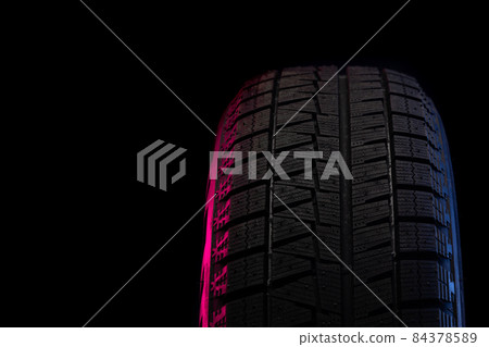part of winter tires on a black background close-up with red-blue backlight part of winter tires on a black background close-up with red-blue backlight 84378589