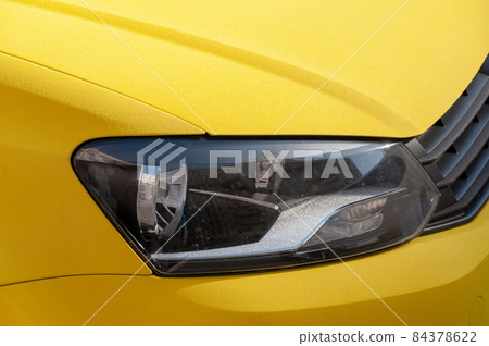 Close-up of a car headlight. Fragment of the car body. Headlamp of auto. 84378622